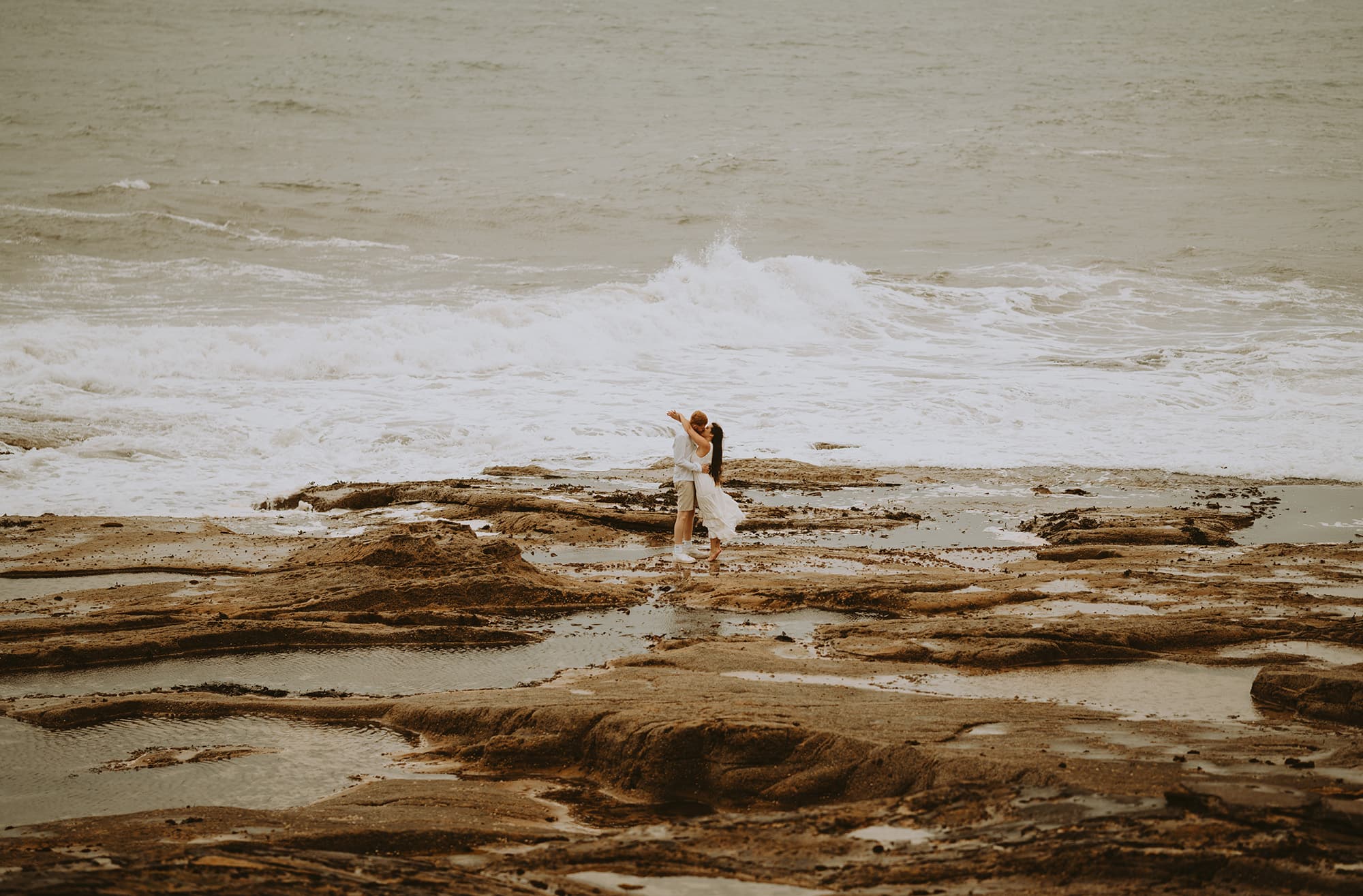 A couple walking hand in hand on the rocky shore